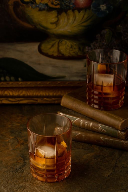 Two glasses of aged rum on a stone surface